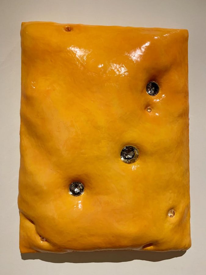untitled (bejeweled cheese), by artist Cara Krebs displays what seems to be cheese and diamonds embedded in it.